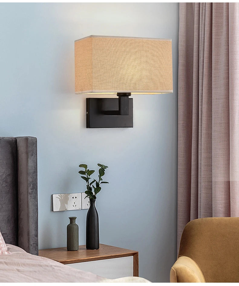 Wall-mounted lamp with a beige shade in a bedroom setting.