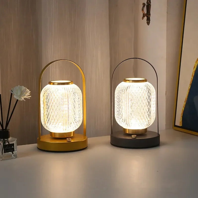 Two table lamps with textured glass shades on a surface, one gold and one black.