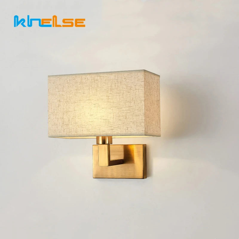 Wall-mounted lamp with gold fixture and beige shade on a light gray background, featuring the brand 'KHELSE'.