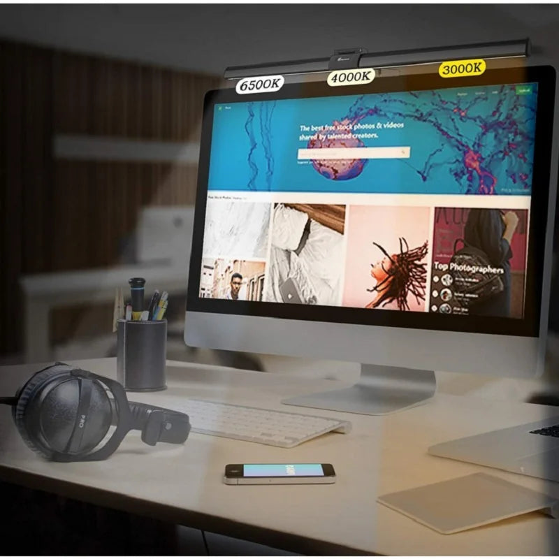 Computer monitor on a desk with a smartphone and headphones, displaying color temperature options.