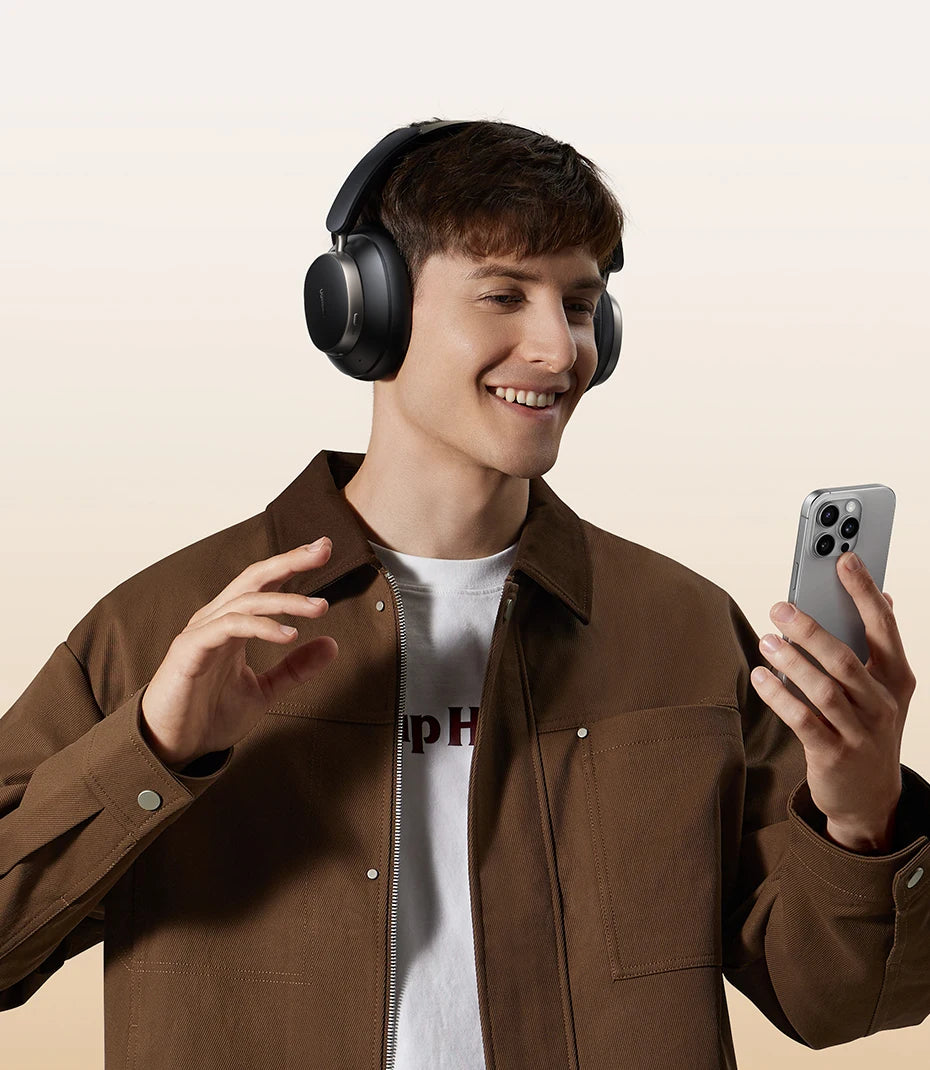 Man wearing headphones and holding a phone, smiling on a beige background