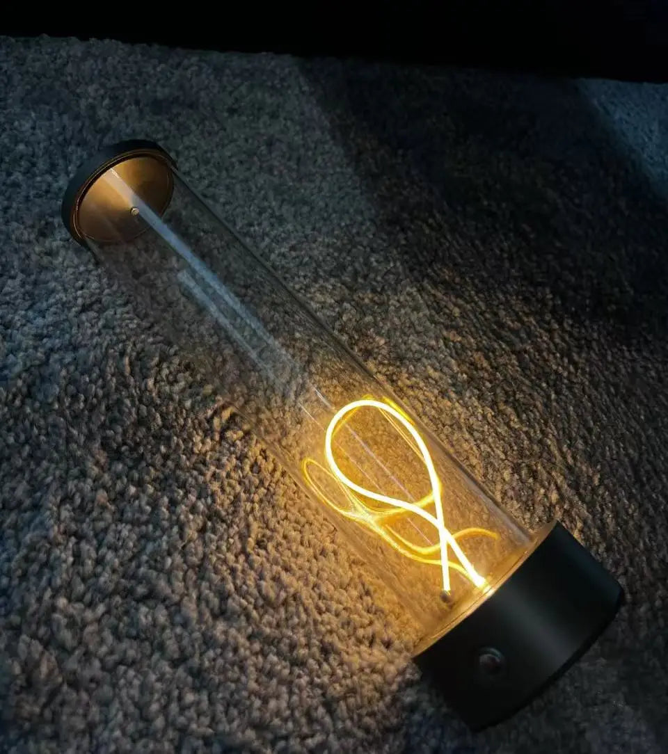 Glass bottle with glowing internal filament on a textured surface