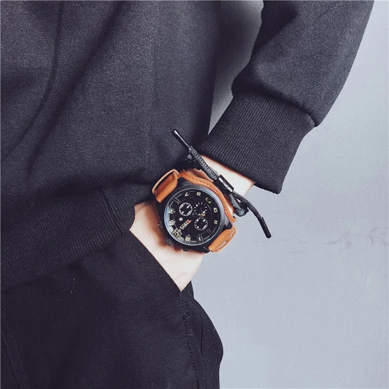 Hand wearing a black watch with brown leather strap against a gray background