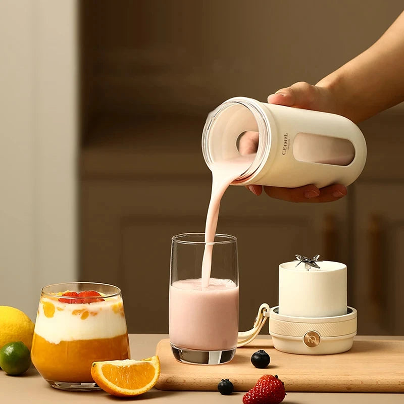Person pouring a creamy liquid from a white container into a glass on a wooden table with fruits and a candle.